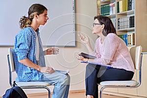 Woman school psychologist talking and helping student, teenage boy