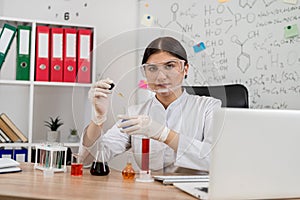 Woman scientist chemist mixing liquid in laboratory glass with pipette,