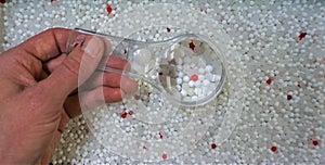 Handheld magnifying glass enlarges view of plastic microbeads photo