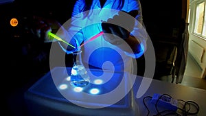 A woman scientist is mixing fluorescent compounds for the synthesis of an antibacterial drug