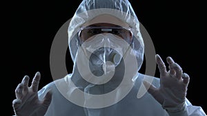 Woman scientist in protective mask, glasses and robe making scary gesture danger