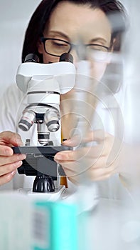 Woman scientist using microscope in laboratory. Microbiology science concept