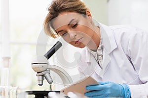 Woman scientist is using microscope and tablet pc in a laboratory during research