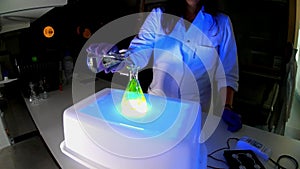 A woman scientist is working in a laboratory with fluorescent compounds for the development