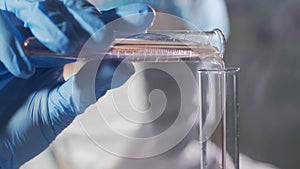 Woman scientist working with liquid in science lab. Close up of female scientist doing laboratory research.