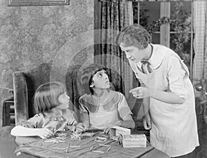 Woman scolding her two daughters for playing with matchsticks