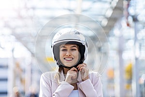 Woman on scooter tightens helmet