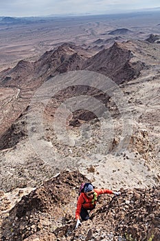 Woman Scrambling Up A Desert Mountain