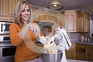 Woman scraping dough in mixer