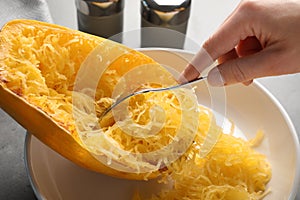 Woman scraping flesh of cooked spaghetti