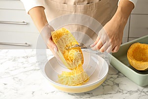 Woman scraping flesh of cooked spaghetti squash