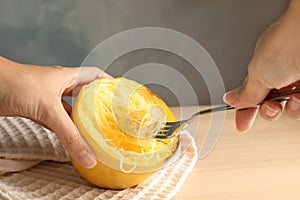 Woman scraping flesh of cooked spaghetti squash