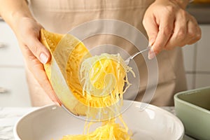 Woman scraping flesh of cooked spaghetti squash