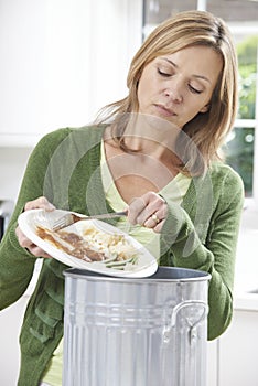 Woman Scraping Food Leftovers Into Garbage Bin photo