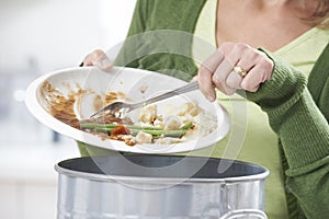 Woman Scraping Food Leftovers Into Garbage Bin photo