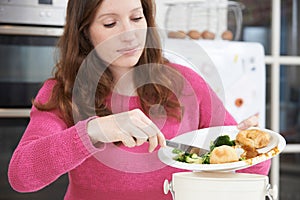 Woman Scraping Food Leftovers Into Garbage Bin