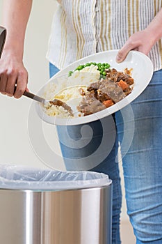 Woman Scraping Food Leftovers Into Garbage Bin