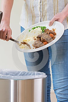 Woman Scraping Food Leftovers Into Garbage Bin photo