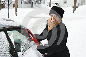 Woman scraping ice off car.