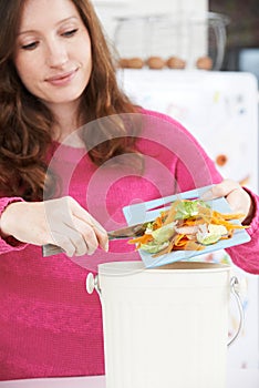 Woman Scraping Vegetable Peelings Into Recycling Bin