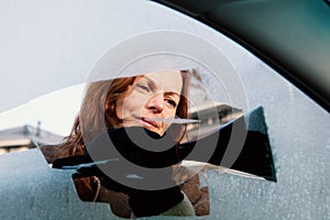 Woman scrapping side window of her car.