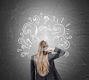 Woman scratching head and question marks on blackboard