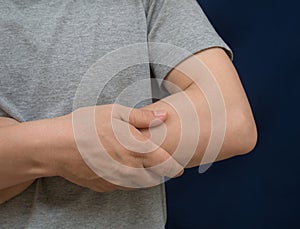 Woman scratching her arm with red spot on black background. Health care concept.
