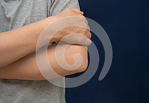 Woman scratching her arm with red spot on black background. Health care concept.