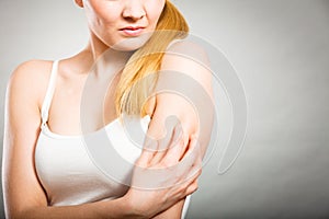 Woman scratching her itchy arm with allergy rash