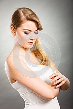 Woman scratching her itchy arm with allergy rash