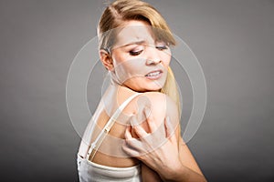 Woman scratching her itchy arm with allergy rash