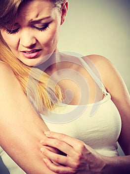 Woman scratching her itchy arm with allergy rash