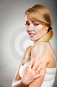 Woman scratching her itchy arm with allergy rash