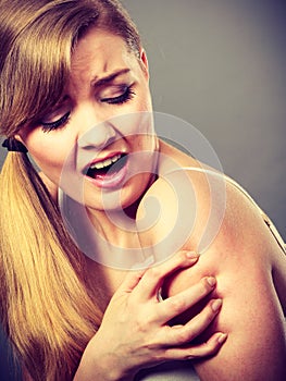 Woman scratching her itchy arm with allergy rash
