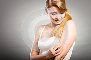 Woman scratching her itchy arm with allergy rash