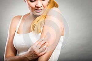 Woman scratching her itchy arm with allergy rash