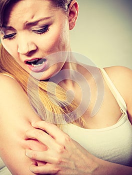 Woman scratching her itchy arm with allergy rash