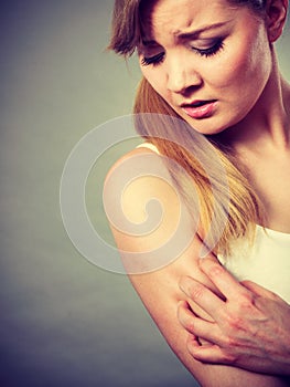 Woman scratching her itchy arm with allergy rash