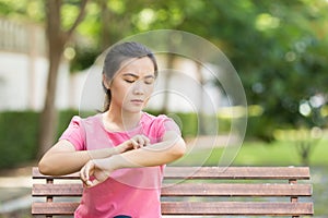 Woman scratching her skin at park garden
