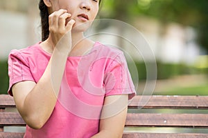 Woman scratching her skin at park garden