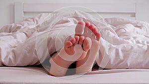 Woman scratching one foot against the other in bed