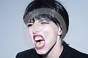 Woman scream close up. Girl with make up screaming on grey background. Angry woman. Girl on scandalous shouting face. photo