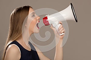 Woman scream in a megaphone. Gray background