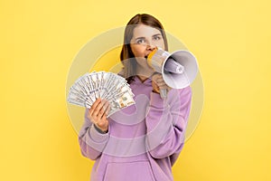 Woman screaming in megaphone holding fan of dollars, announcing bonuses and promotions.