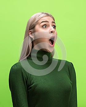 The woman screaming with open mouth isolated on green background, concept face emotion
