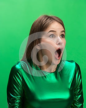 The woman screaming with open mouth isolated on green background, concept face emotion