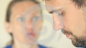 The woman screams at the man. The face of a man in profile is close-up, the woman`s face is blurred.