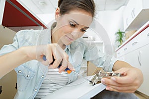 woman screwing hinge to kitchen cupboard door