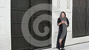 Woman scrolling smartphone while standing by gate