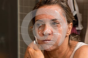 Woman Scrubding her Face in Front of a Mirror
